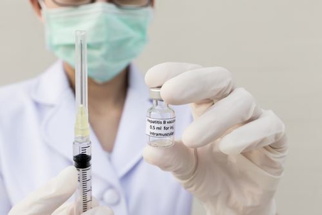 doctor wearing mask holding needle and vile